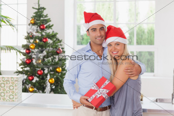 Happy couple holding a gift at christmas