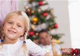 Cute girl by dinner table smiling at christmas