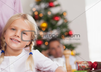 Cute girl by dinner table smiling at christmas