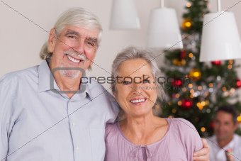 Happy grandparents standing at christmas by dinner table