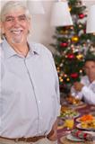 Happy grandfather standing at christmas by dinner table