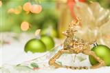 Beautiful Golden Christmas Reindeer Ornament Among Snow, Bulbs and Ribbon Against an Abstract Background.