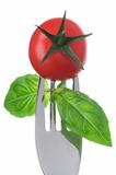 tomato and basil on a fork on white