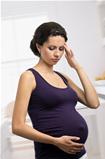 Pregnant woman standing with headache at home