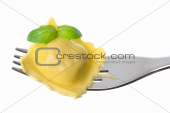 ravioli pasta parcel and basil garnish on fork white background