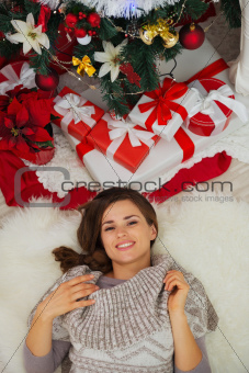 Portrait of happy young woman laying near Christmas tree