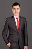Young businessman standing on grey background