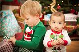 Cute Infant Baby and Young Boy Enjoying Christmas Morning Near The Tree.