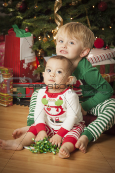 Cute Infant Mixed Race Baby and Young Boy Enjoying Christmas Morning Near The Tree.