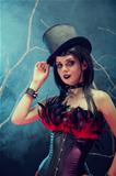 Attractive smiling gothic girl in tophat and feather corset 