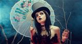 Attractive gothic girl in top hat with Chinese umbrella looking 