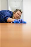 Professional female cleaner wiping table in office