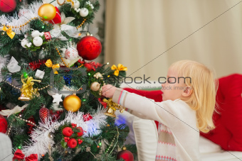 Baby girl decorating Christmas tree