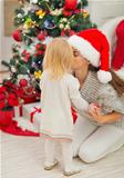 Mother kissing baby near Christmas tree