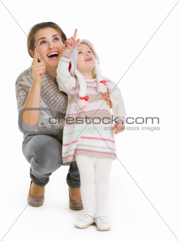 Christmas portrait of happy mother and baby girl pointing up on copy space