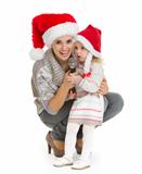 Christmas portrait of happy mother and baby girl singing into microphone