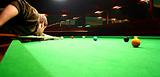 Young man shooting a red ball. Snooker game.