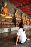 A girl watching status of golden buddha inside Wat Suthad temple