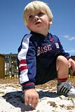 Blonde boy playing in sandy playground