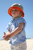 Blonde boy standing on sunny beach
