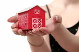 The red house is in a female hand on a white background