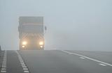 Truck appearing through fog with headlights on