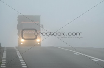 Truck appearing through fog with headlights on