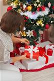 Woman putting present box under Christmas tree