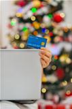 Closeup on credit card and laptop in front of Christmas tree