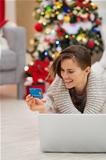 Happy woman near Christmas tree shopping online