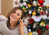 Happy woman near Christmas tree making phone call