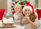 Happy mother and baby eating Christmas cookies