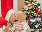 Mother and baby kissing near Christmas tree