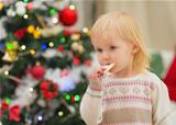 Baby eating Christmas cookies near Christmas tree