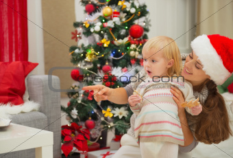Eat smeared baby and mother near Christmas tree looking on copy space