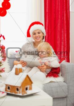 Happy mother and baby using tablet PC near Christmas tree