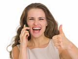 Portrait of happy woman talking mobile and showing thumbs up