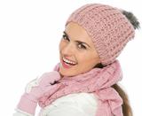 Smiling woman in knit scarf, hat and mittens looking back