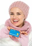 Happy woman in knit winter clothing showing credit card