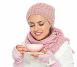 Happy young woman in knit winter clothing enjoying cup of hot tea