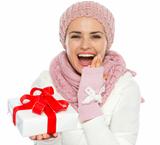 Surprised young woman in knit winter clothing holding Christmas present box