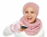 Closeup on TV remote control in hand of happy woman in knit winter clothing