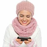 Smiling woman in knit winter clothing writing text message