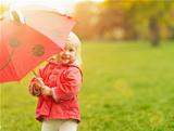 Smiling baby looking out from red umbrella