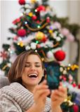 Happy woman near Christmas tree making self photo
