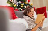 Happy woman with book near Christmas tree