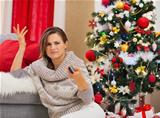 Frustrated woman with TV remote control near Christmas tree