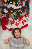 Happy woman laying near Christmas tree and pointing in camera