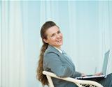 Happy business woman sitting with laptop