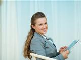 Happy business woman sitting with tablet PC